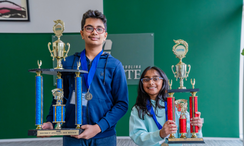  Dhruva Srivatsa (left) and Anika Ladde (right) smiling and holding their Spelling Bee trophies.